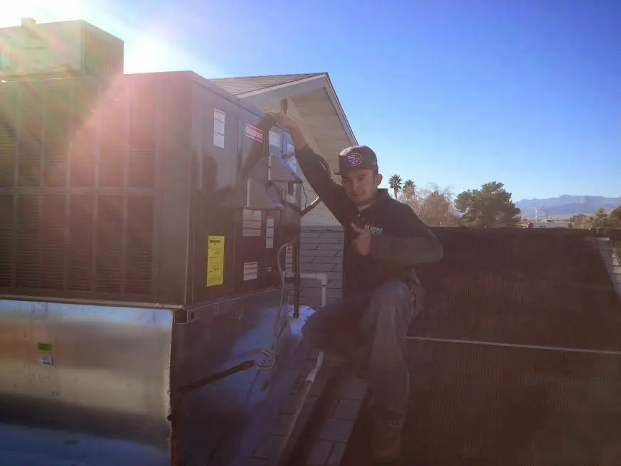 HVAC technician performing Air Duct Cleaning on a rooftop unit in Grand Rapids